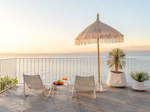 Seaside terrace with sun loungers and umbrella at sunset overlooking the Cretan Sea.