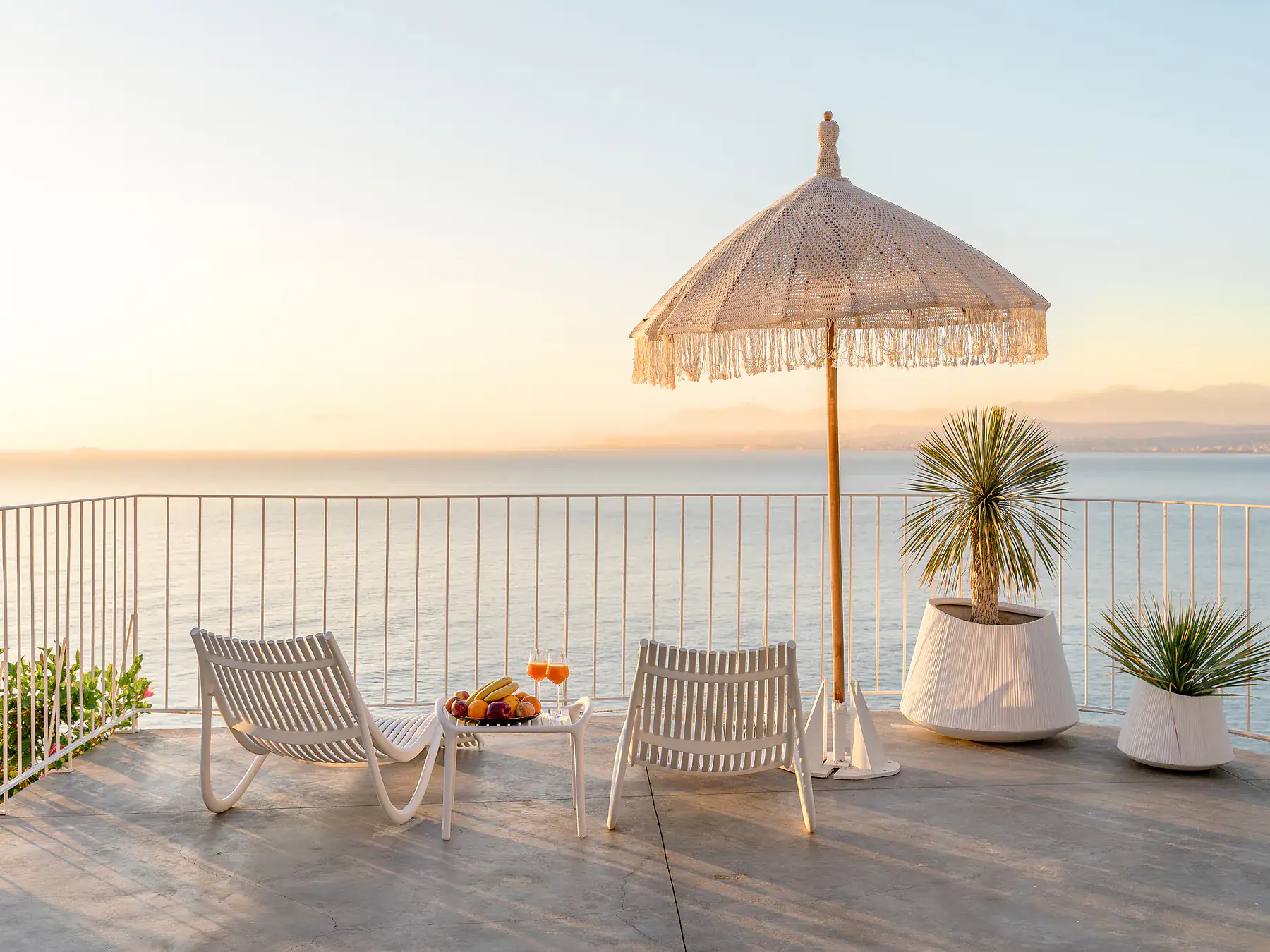 Seaside terrace with sun loungers and umbrella at sunset overlooking the Cretan Sea.
