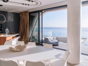 Open dining and living area with retractable glass doors and sea-facing terrace.