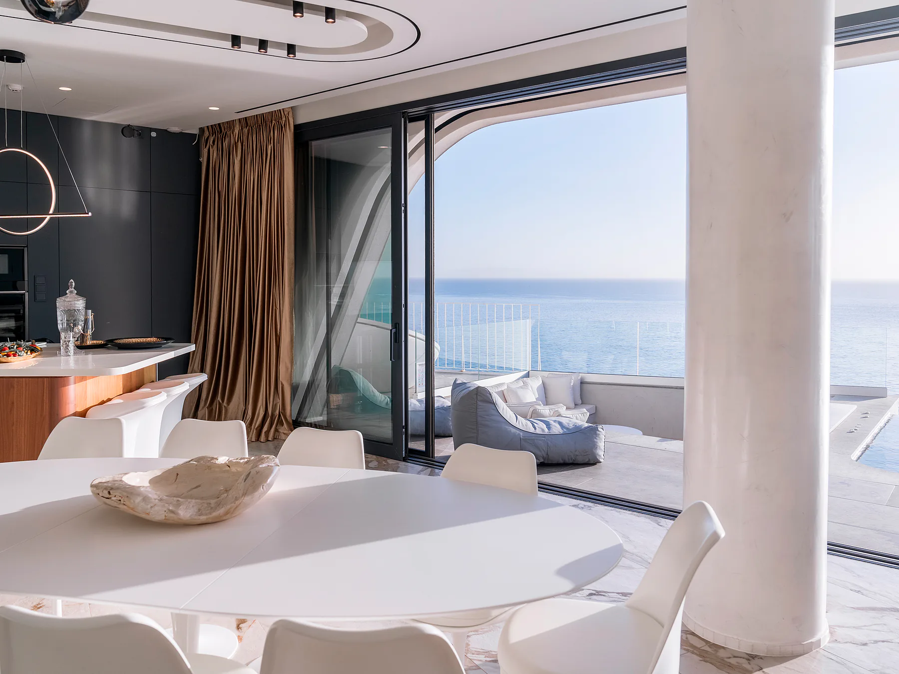 Open dining and living area with retractable glass doors and sea-facing terrace.
