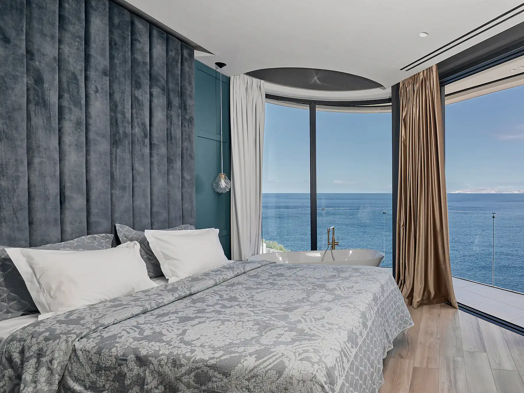 Spacious bedroom with floor-to-ceiling windows and modern blue-gray decor.