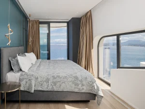 Minimalist bedroom with glass balcony overlooking the Mediterranean.