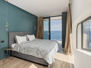 Cozy bedroom with ocean-facing windows and natural light.