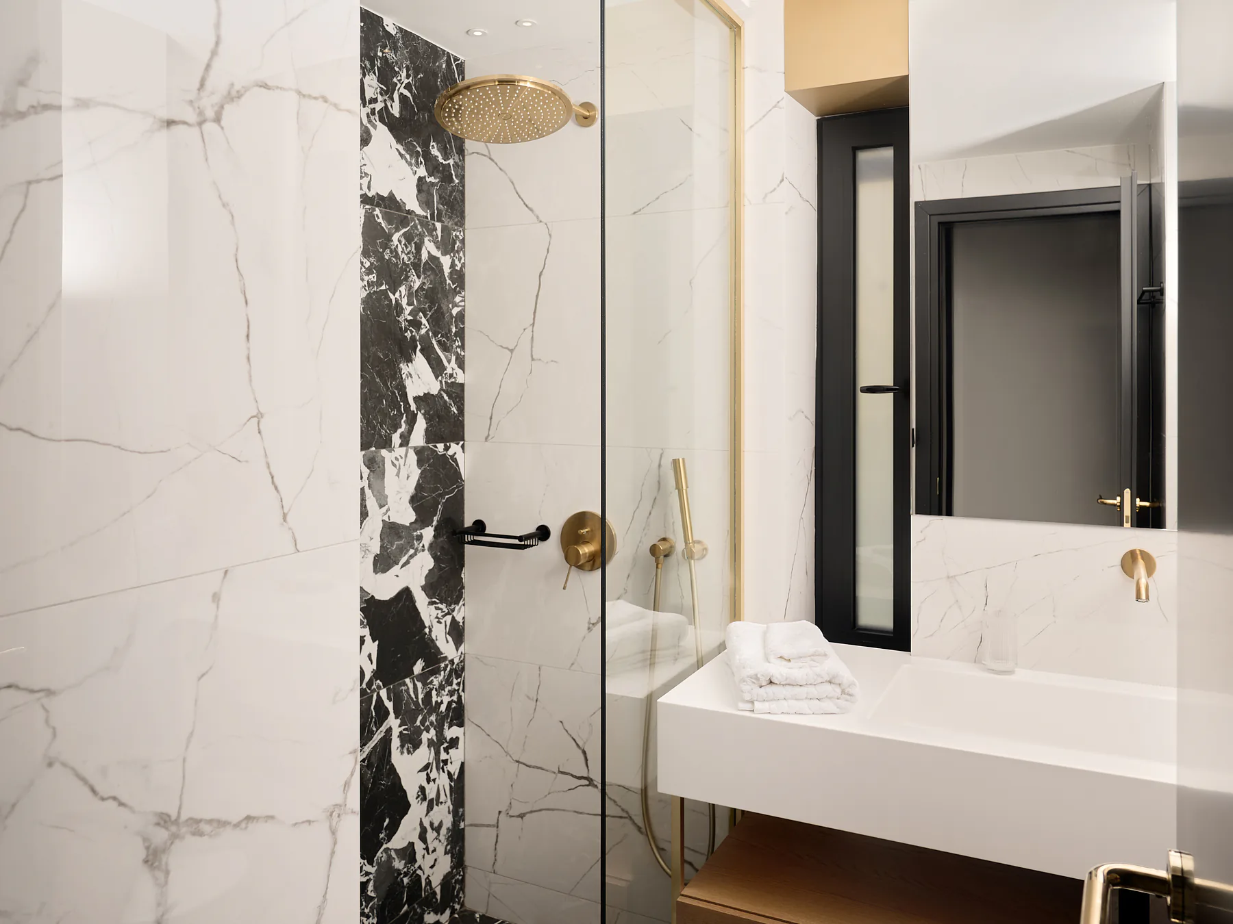 Luxury bathroom with marble finishes, walk-in shower, and gold fixtures.