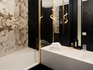 Black and white marble bathroom with deep soaking tub and gold details.
