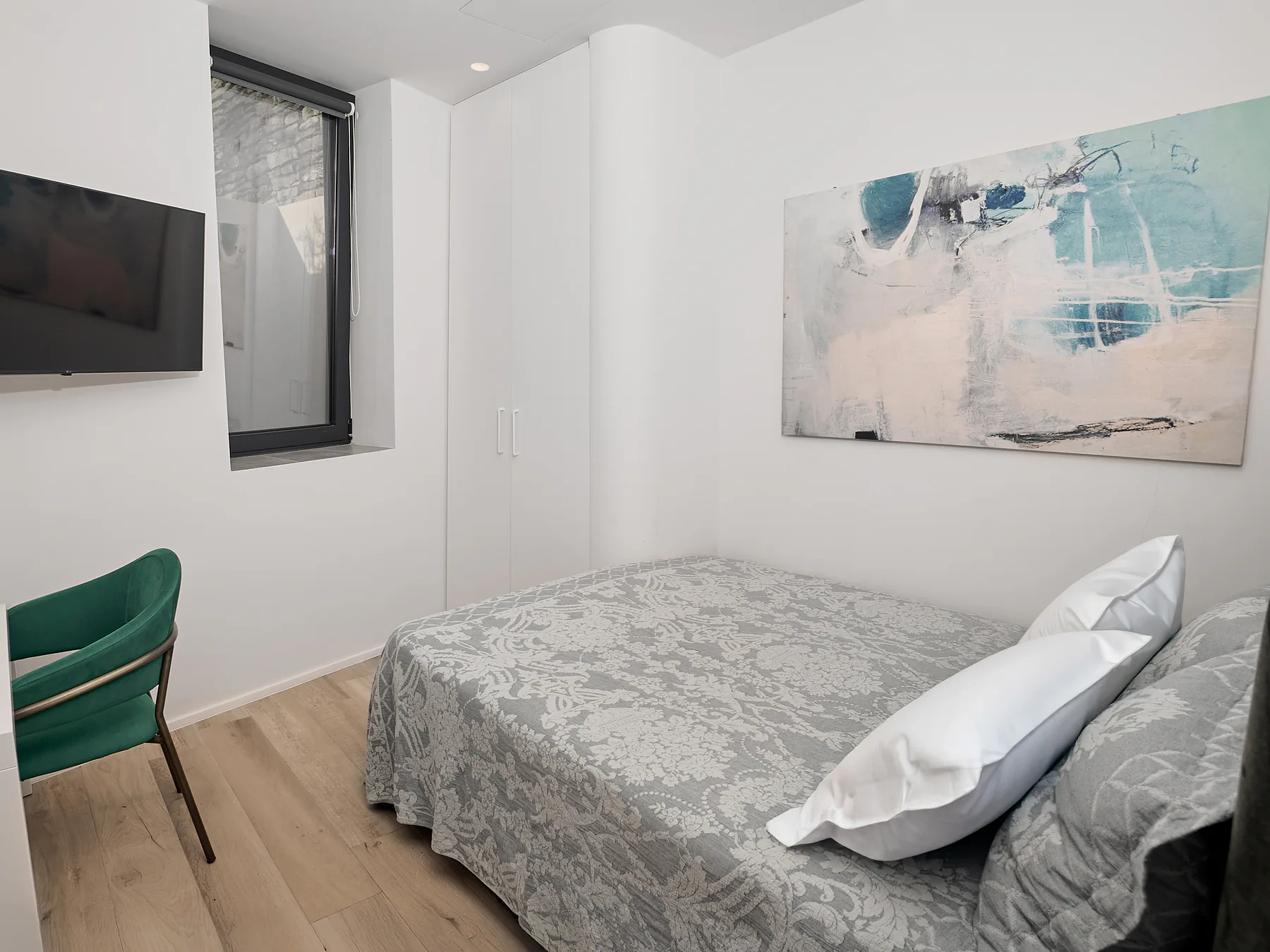 Compact double bedroom with modern art and warm lighting in Meltemi Villa.