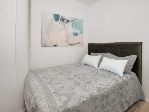Bright guest bedroom with light gray bedding and soft neutral design tones.