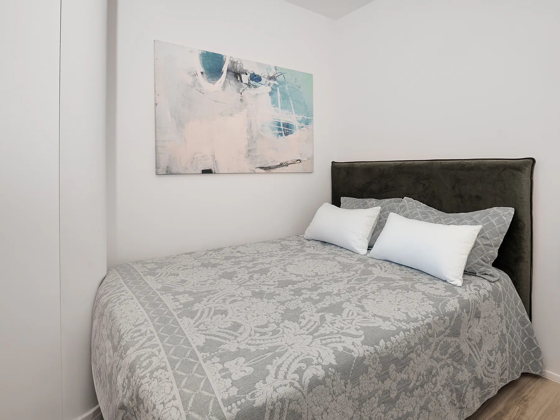 Bright guest bedroom with light gray bedding and soft neutral design tones.