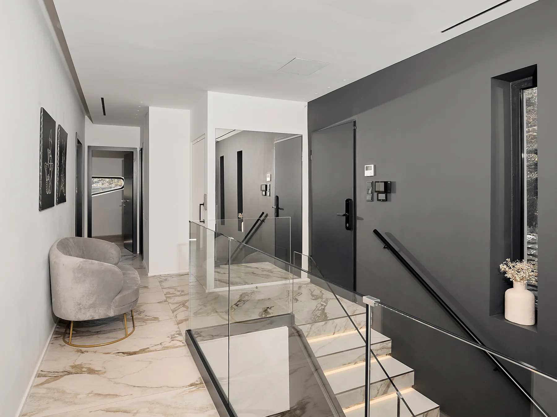 Modern interior staircase with glass railing and marble flooring inside Meltemi Villa.